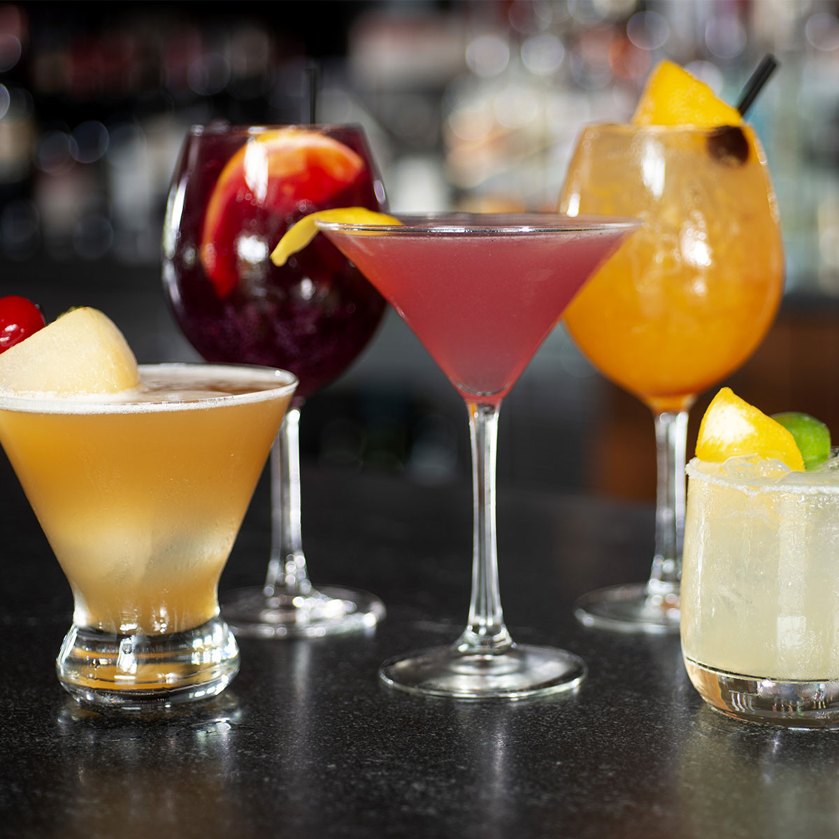 A selection of different colored cocktails with fruit adornments at Burtons Boca Raton location