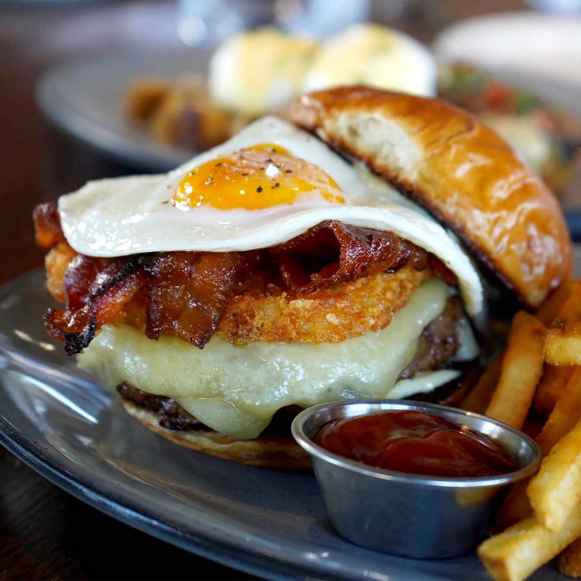 Breakfast burger topped with fried egg and bacon at Burtons Grill's Brunch